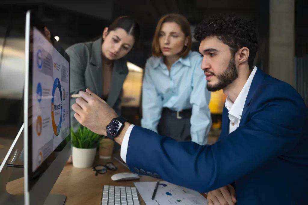 Team of professionals analyzing financial graphs on a computer screen during a business meeting in an office.